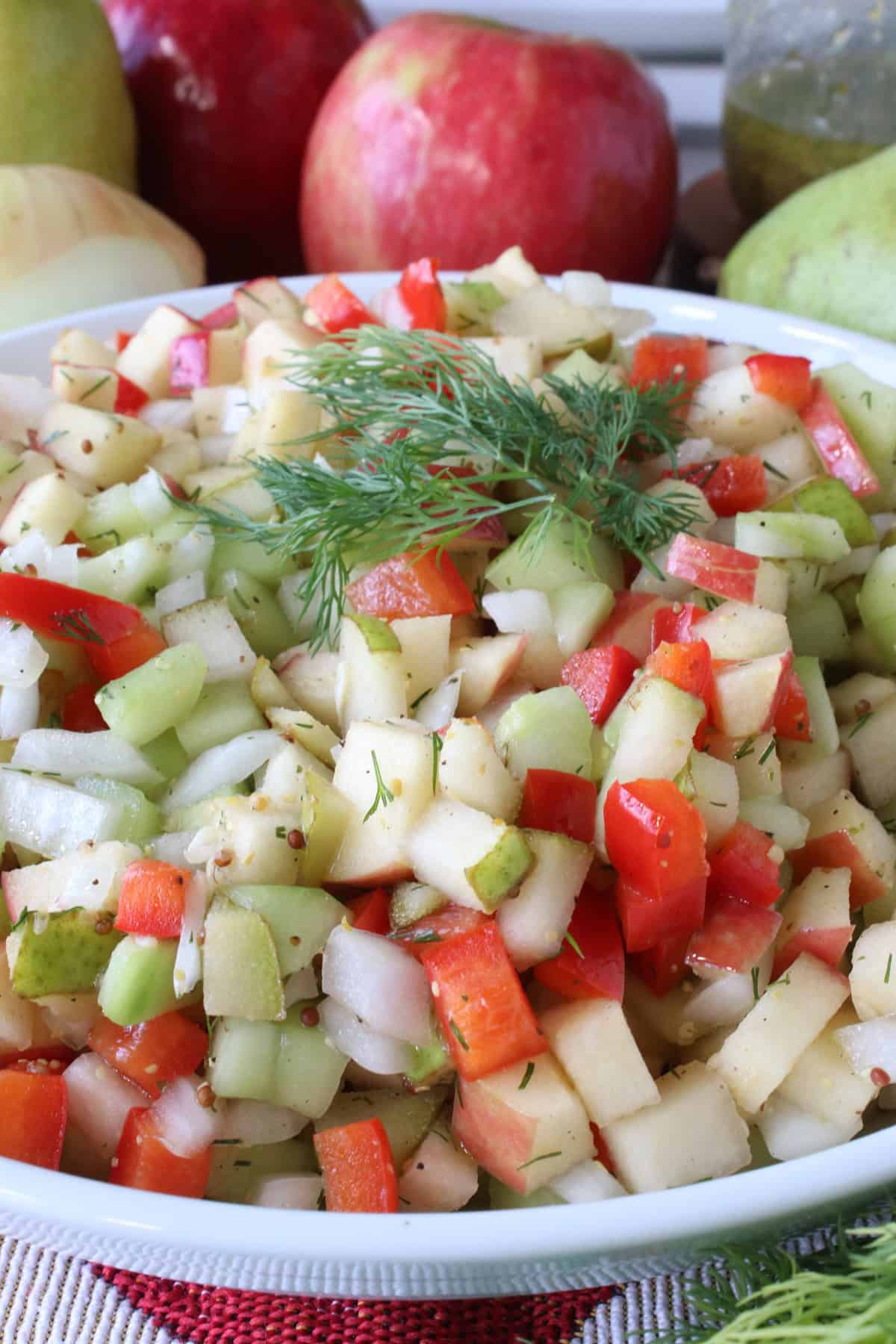 Fresh dill on top of a chopped cucumber and fruit salad.