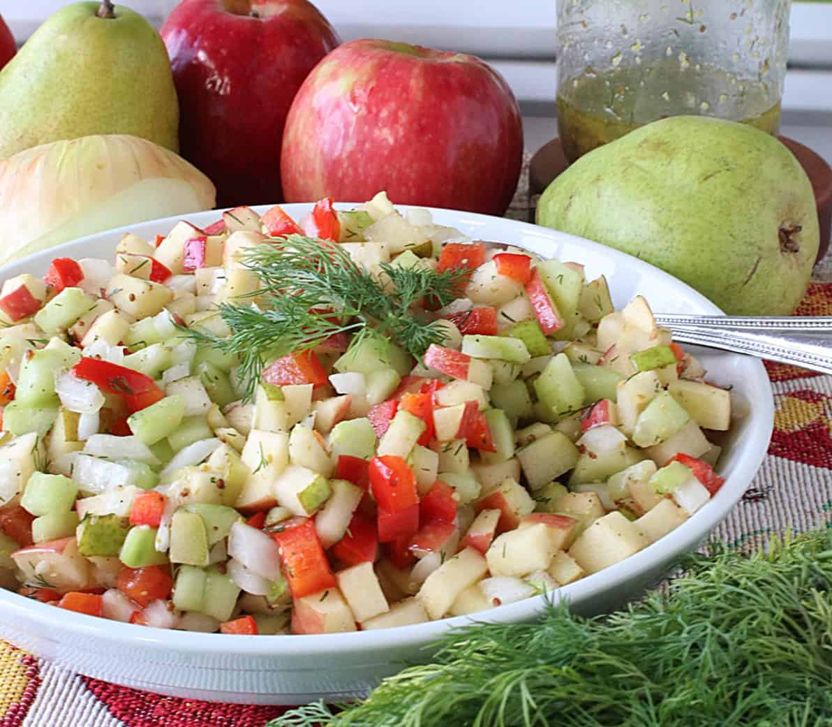 A cucumber and fruit salad in a white bowl.