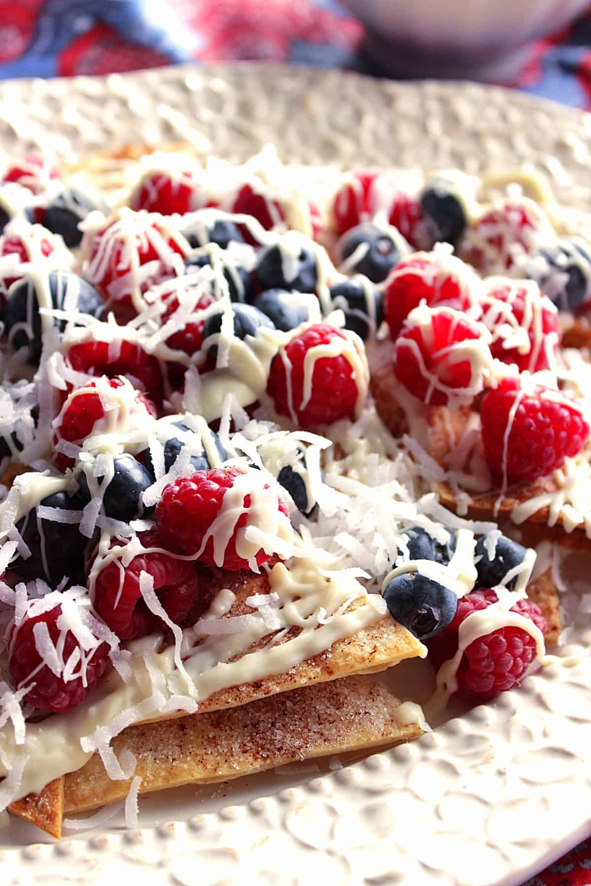 A white chocolate drizzle on top of fresh berries and cinnamon sugar nachos.