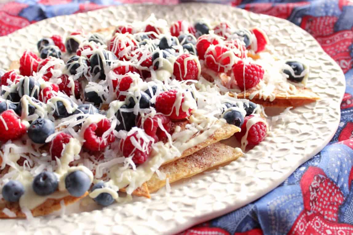 A colorful platter of red, white and blue dessert nachos topped with white chocolate.
