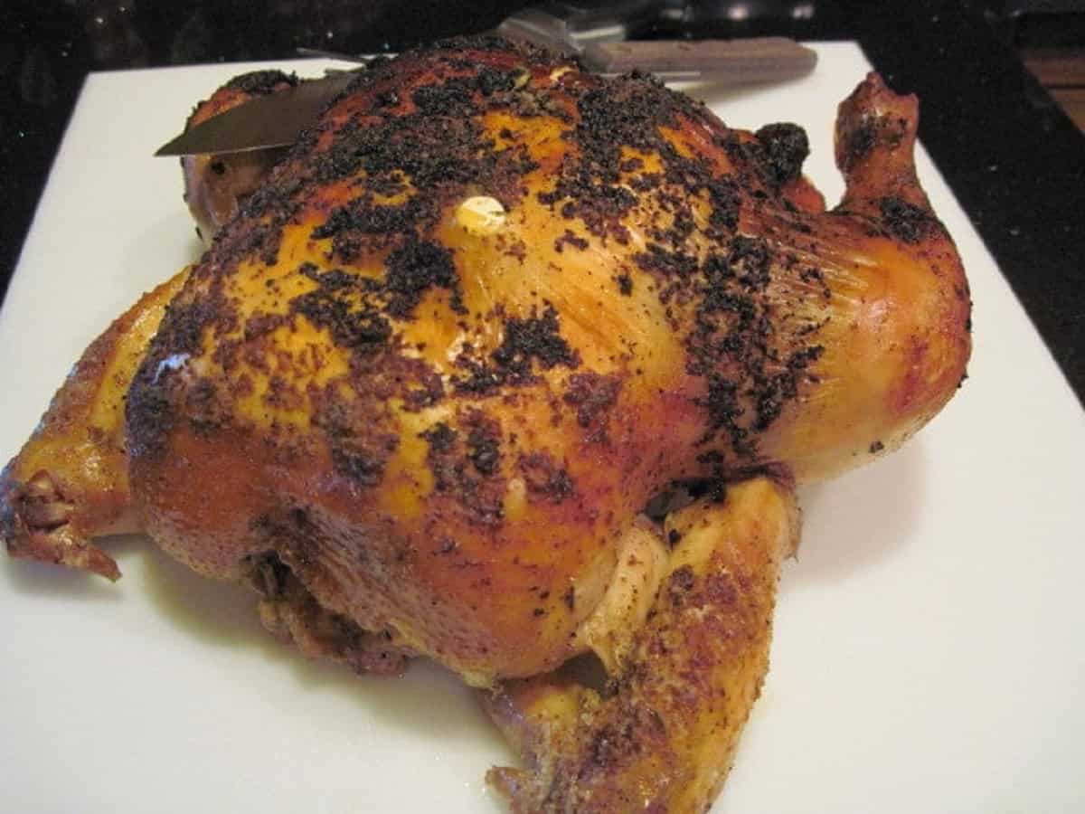 A whole golden Roasted Beer Chicken on a white cutting board.