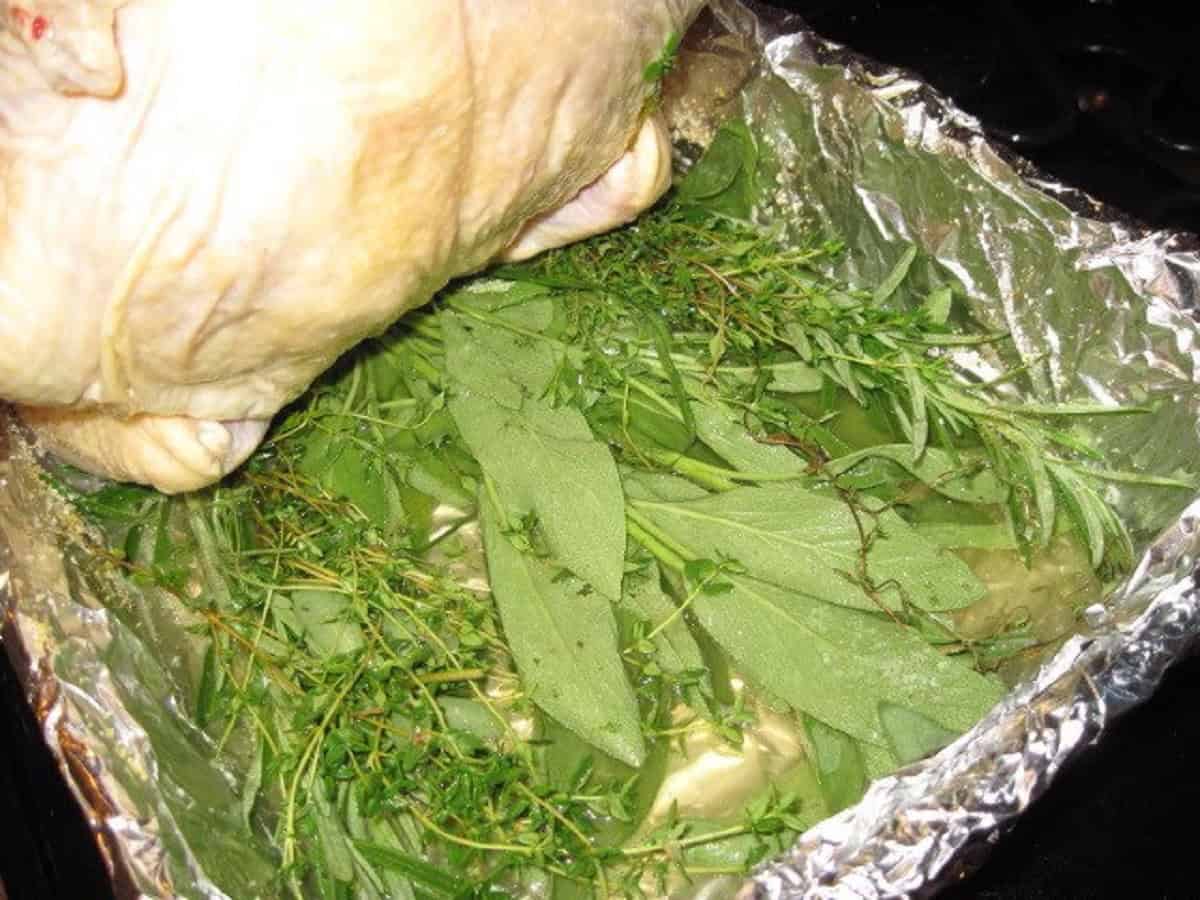 Fresh herbs in a roasting pan for making beer chicken.
