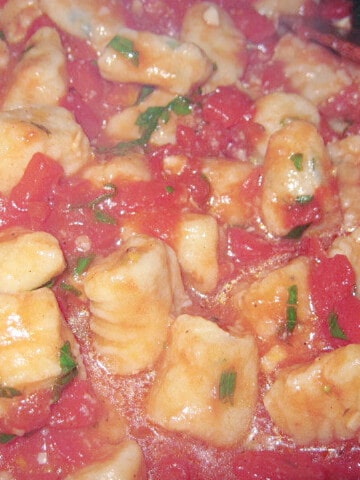 A closeup photo of Ricotta Gnocchi in a tomato sauce.