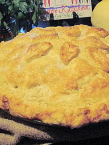 A fully baked Apple Pear Pie with Craisins including some pie crust leaves on top.