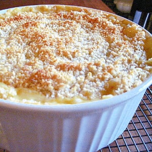 A round white casserole dish filled with Sweet and Cheesy Onion Casserole with a crunchy topping.