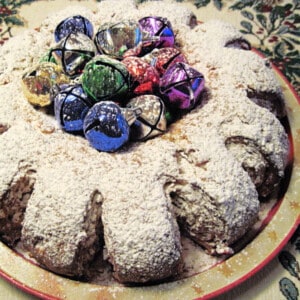 A traditional German Stollen decorated with multi colored bells and powdered sugar on top.