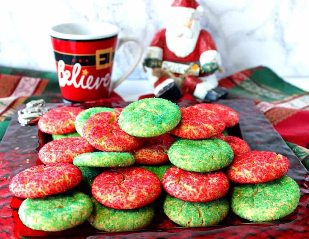 A plate full of Santa's Favorite Sugar Cookies with a wooden Santa in the background.
