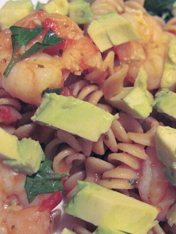 A closeup of a serving of Spicy Shrimp Pasta with avocado and cilantro.