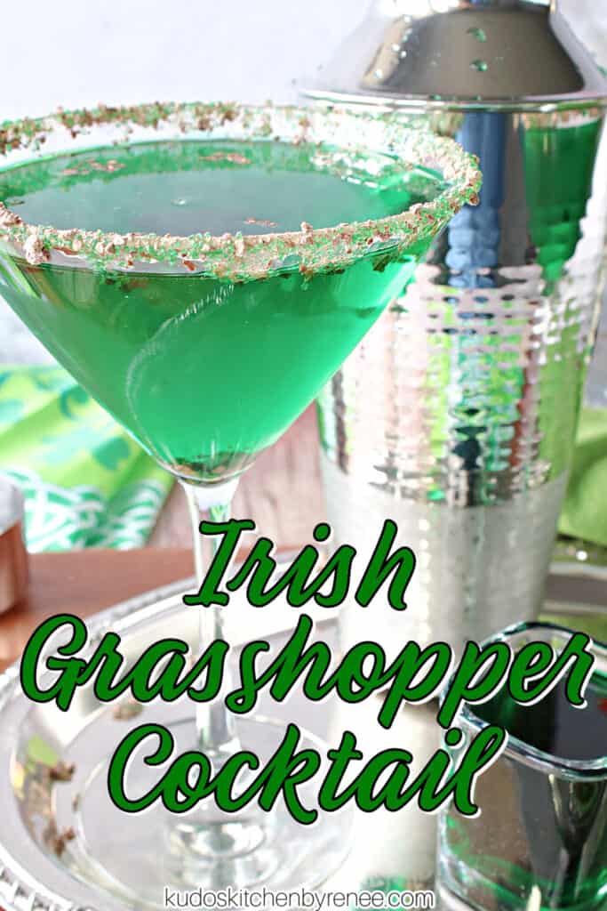 A vertical closeup photo of a martini glass filled with a green Irish Grasshopper Cocktail, and a cocktail shaker on a silver platter along with a title text overlay graphic.