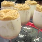 Five wine glasses filled with Banana Panna Cotta with a crumble topping.