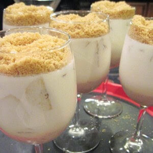 Five wine glasses filled with Banana Panna Cotta with a crumble topping.