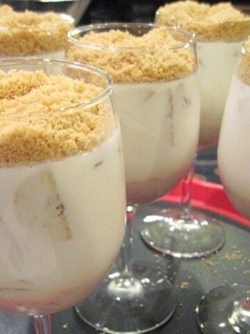Five Banana Pana Cotta served in wine glasses with a crumb topping.
