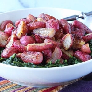 A white bowl filled with Roasted Radishes and greens.