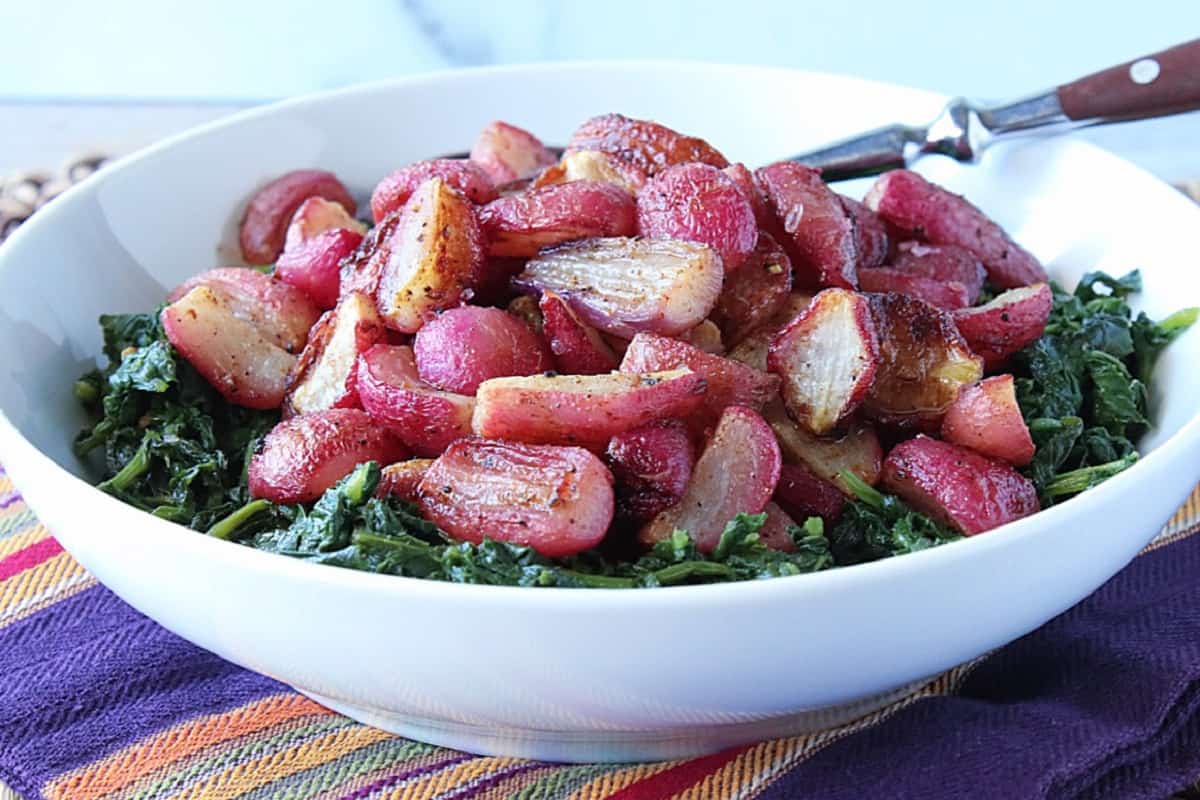 A white bowl filled with Roasted Radishes and greens.