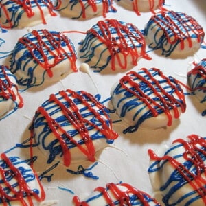 A bunch of Red, White, and Blue Chocolate Dipped Cookies on a baking sheet with parchment paper.