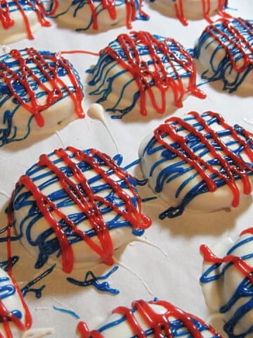 A bunch of Red, White, and Blue Chocolate Dipped Cookies on a baking sheet with parchment paper.