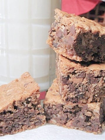 A stack of Chocolate Chip Cookie Bars and a glass of milk in the background.