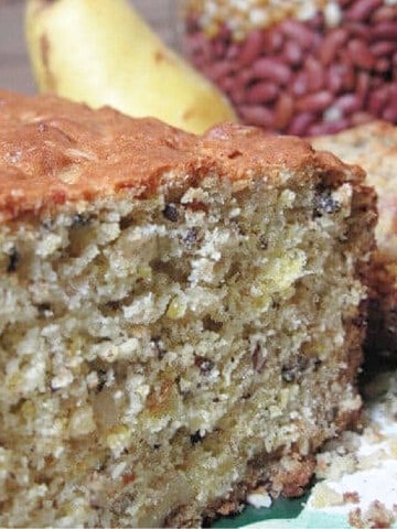 A sliced loaf of Cheddar Pear Bread with a pear in the background.