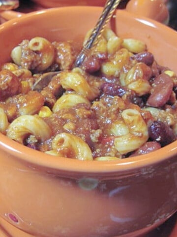 A orange mug filled with Drunken Turkey Chili Mac with pasta and beans.