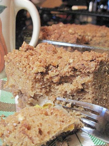 A serving of Peach Coffee Cake on a plaid plate with a fork.