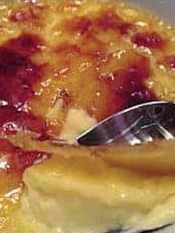 A spoon cracking into the sugar topping of an Orange Creme Brulee.