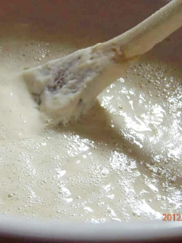 A closeup of bubbly Sourdough Starter with a wooden spoon.