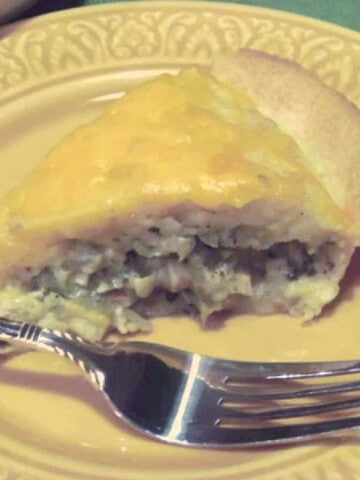 A slice of Chicken Quesadilla Pie with melted cheese and a fork on a yellow plate.