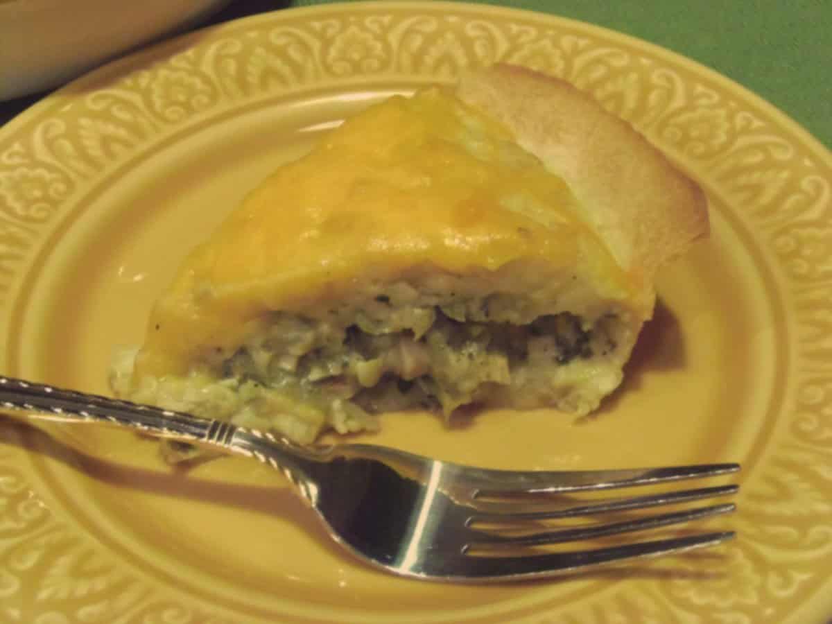 A slice of Chicken Quesadilla Pie with melted cheese and a fork on a yellow plate.