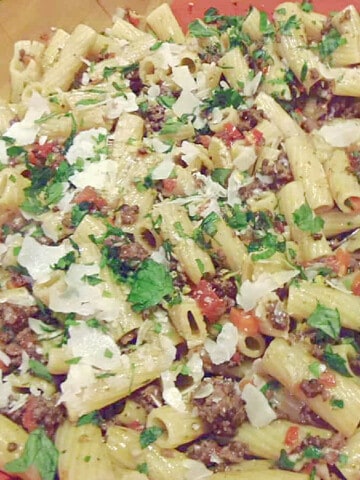 A closeup photo of Rigatoni with Meat Sauce with cheese and parsley.