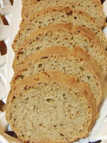 An overhead photo of a white ceramic bread bowl filled with slices of Sourdough Rye Bread with Dill slices.