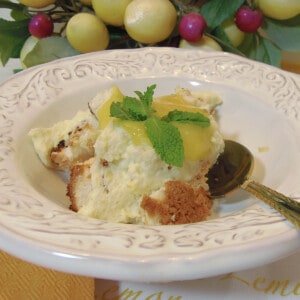 A pretty white bowl filled with Angle Food Trifle with Lemon Curd Whipped Cream and some mint leaves.
