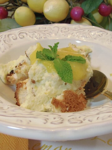 A pretty white bowl filled with Angle Food Trifle with Lemon Curd Whipped Cream and some mint leaves.