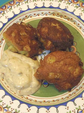 Three Corn Fritters with Adobo Sauce on a colorful plate.