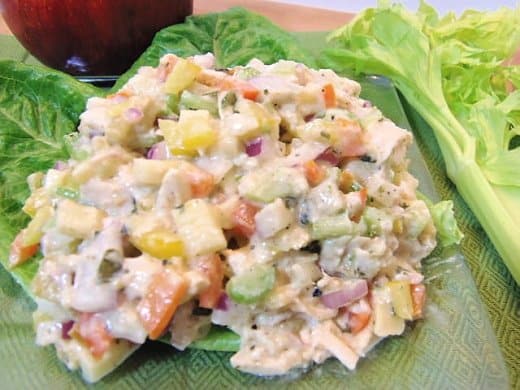 A colorful closeup of a serving of Rainbow Chicken Salad on a bed of lettuce leaves.