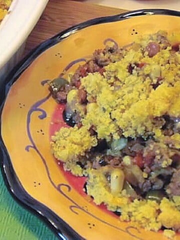 A colorful black rimmed yellow plate filled with a serving of Ground Beef Tamale Casserole.