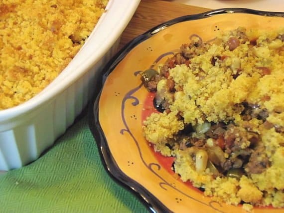 A colorful black rimmed yellow plate filled with a serving of Ground Beef Tamale Casserole.