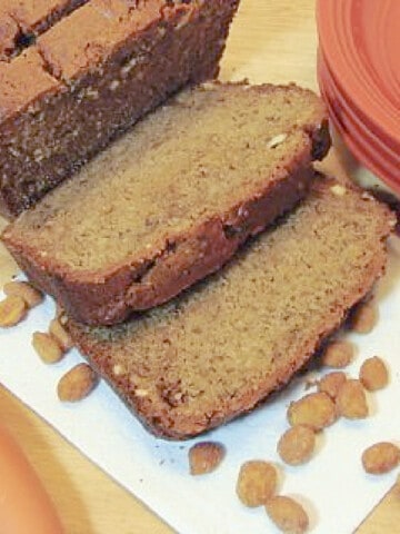 A sliced loaf of Peanut Butter Banana Quick bread with honey roasted peanuts on the table.