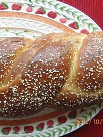 A twisted loaf of Homemade Challah Bread topped with poppy and sesame seeds.