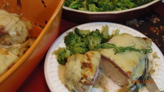 A serving of Unstuffed Chicken Cordon Bleu on a white plate with melted cheese and broccoli.