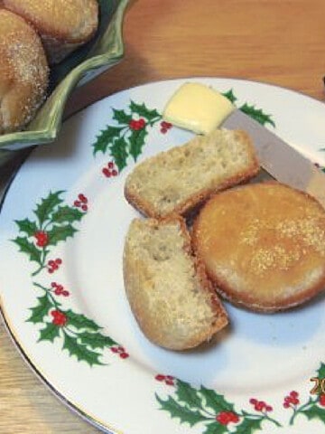 Two English Muffin Muffins on a holiday plate with a knife and a pat of butter.