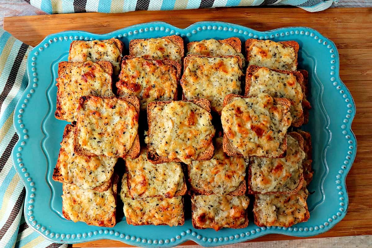 A blue platter filled with Parmesan Onion Square Appetizers.