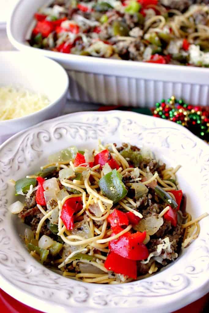 A vertical closeup photo of a bowl of Christmas pasta with red and green peppers. Christmas dinner recipe roundup.