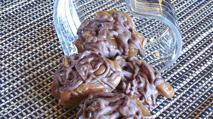Homemade Pecan Turtle Candy spilling out of a glass heart candy dish.