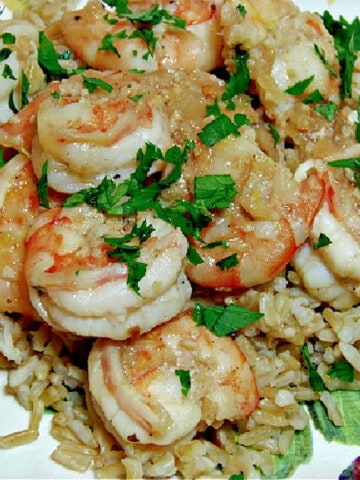 A closeup photo of Skinny Shrimp Scampi on a plate with brown rice and chopped parsley.