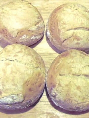 A closeup photo of Homemade Kaiser Rolls on a wooden board.