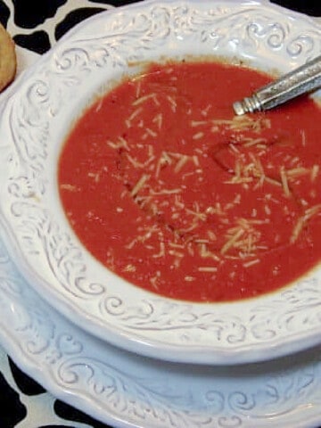 A serving of Tomato and Red Pepper Soup in a white bowl on a black and white tablecloth.
