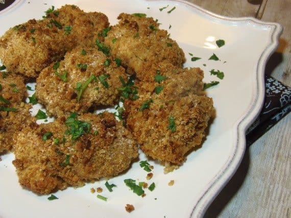 A white plate filled with Oven Fried Chicken Thighs and a parsley garnish.