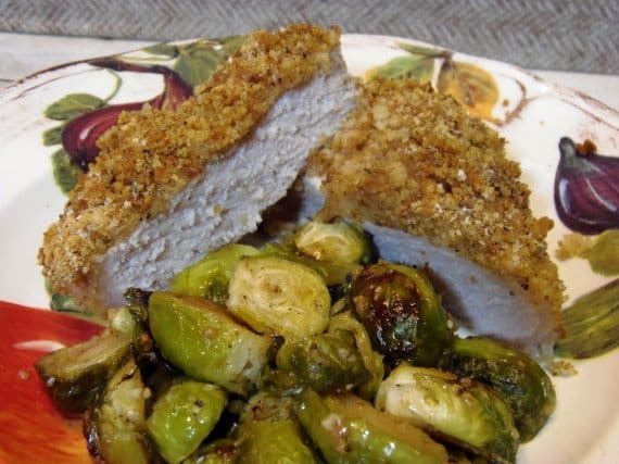 A Breaded Pork Chop that's been cut in half on a dinner plate.