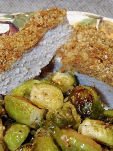 A Breaded Pork Chop that's been cut in half on a dinner plate.