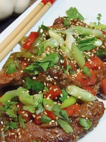 A colorful serving of Mongolian Beef on a white plate.